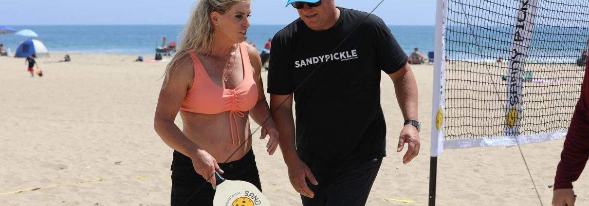 couple about to play pickleball on the beach