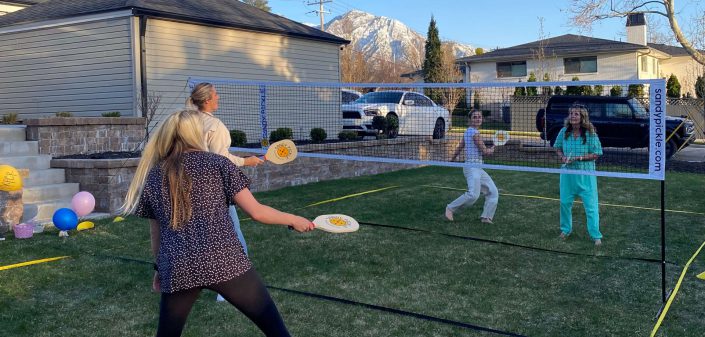 Family playing grass pickleball on their backyard pickleball court